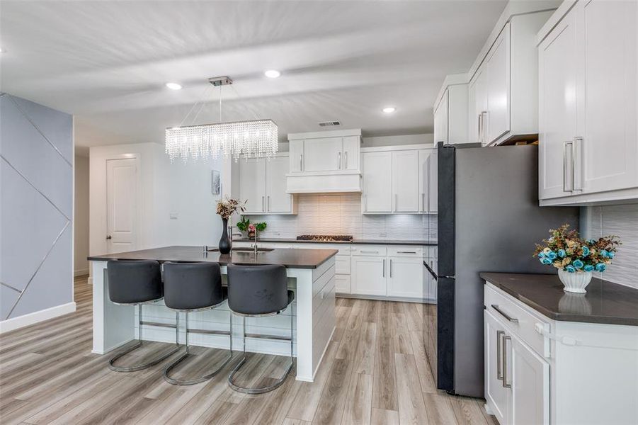 Light and bright chef's kitchen with stunning backsplash, a center island with sink, a breakfast bar, light luxury vinyl plank wood finished floors, stunning white cabinetry with luxury lighting! Light and bright chef's kitchen with stunning backsplash, a center island with sink, a breakfast bar, light luxury vinyl plank wood finished floors, stunning white cabinetry with luxury lighting!