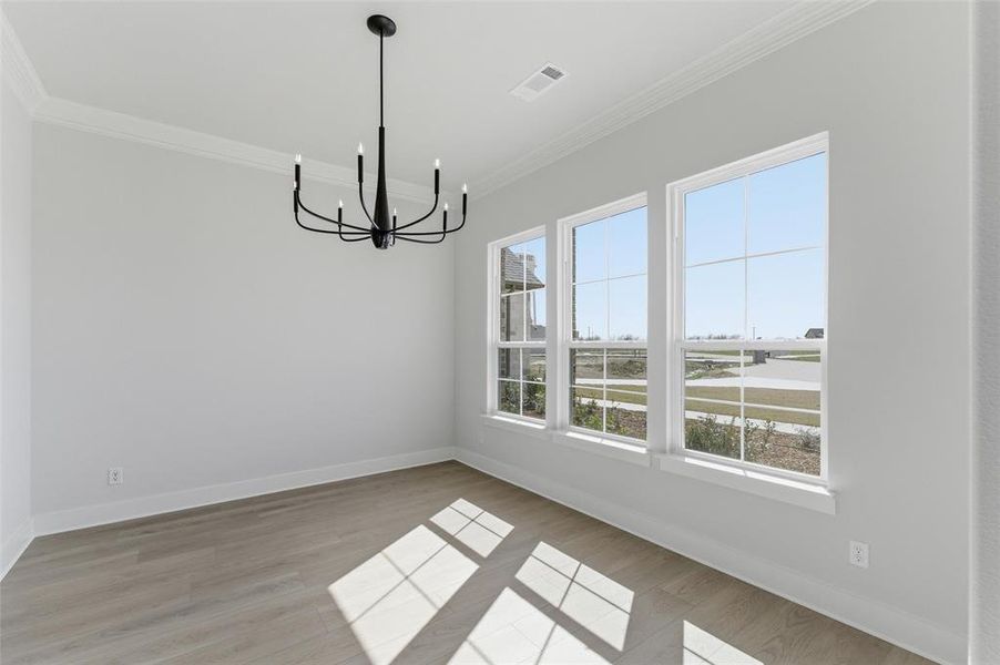 Unfurnished dining area with light wood-type flooring, crown molding, and suspended lighting Unfurnished dining area with light wood-type flooring, crown molding, and suspended lighting