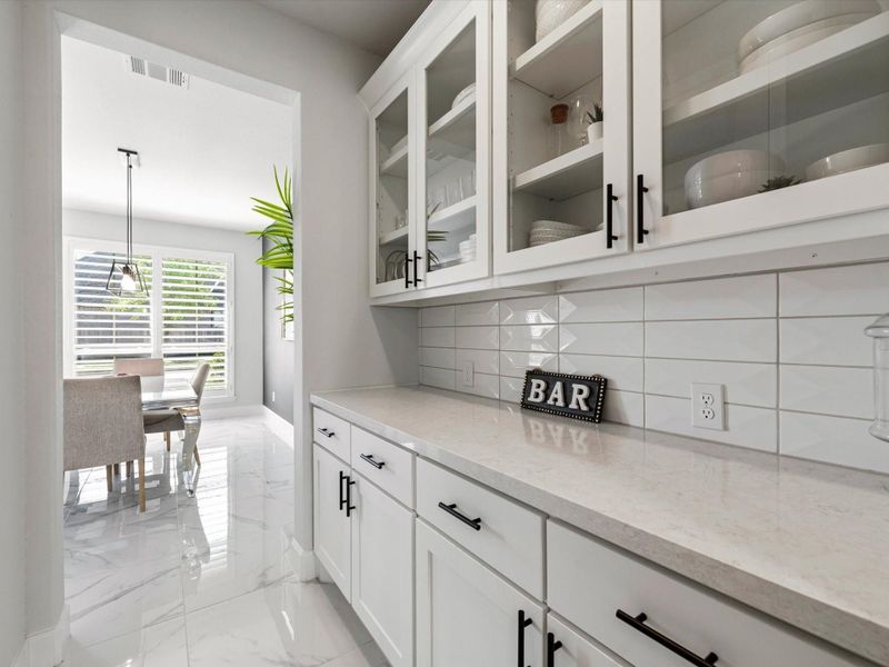 Look at all the glass-front uppers and drawers and cabinets below. Counter has space for a bar set and your coffee set up for mornings too!