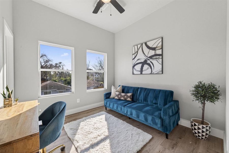 Flexible secondary bedroom or home office with oversized windows, white oak–finish flooring, and a bright, airy layout perfect for remote work or guest accommodations.