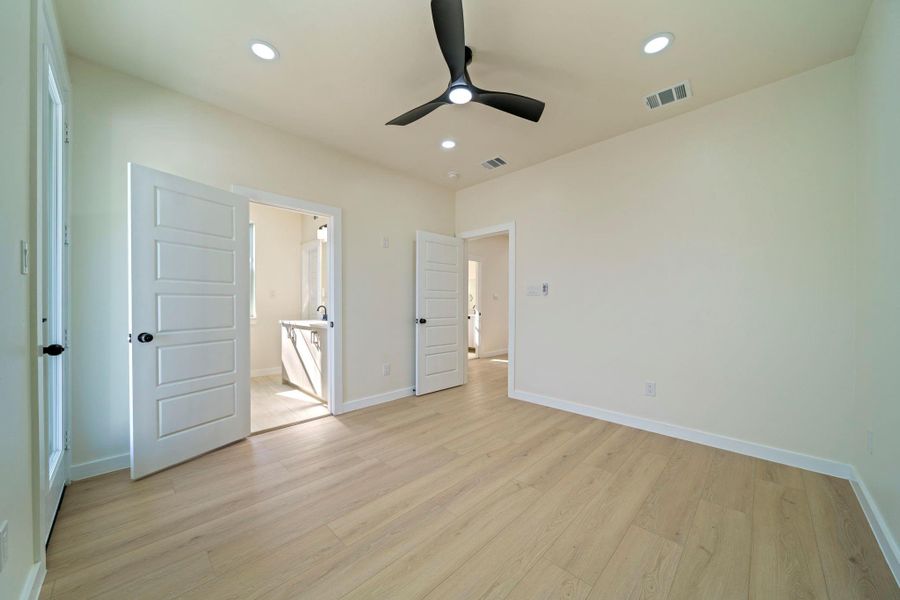 Spacious primary bedroom with elegant flooring, a modern ceiling fan, and convenient access to a bright en-suite bathroom. Spacious primary bedroom with elegant flooring, a modern ceiling fan, and convenient access to a bright en-suite bathroom.