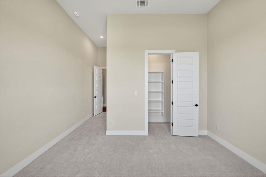 Unfurnished bedroom with light colored carpet, a walk in closet, and recessed lighting Unfurnished bedroom with light colored carpet, a walk in closet, and recessed lighting
