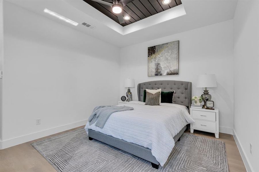 Bedroom featuring a raised ceiling, ceiling fan, and light wood-type flooring