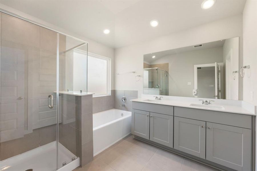 This primary bathroom is definitely move-in ready! Featuring a spa like walk-in shower with tile surround, separate garden tub for soaking after a long day with custom tile detailing, grey cabinets with light countertops, spacious walk-in closet with shelving, high ceilings, sleek and modern finishes.