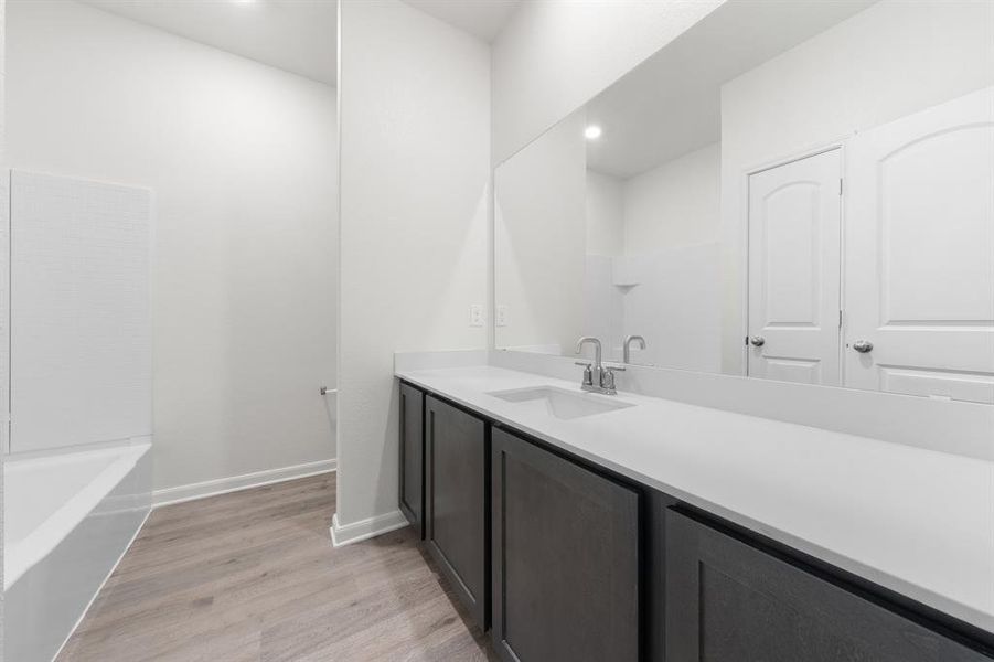 Bathroom featuring bathing tub / shower combination, wood-type flooring, and vanity