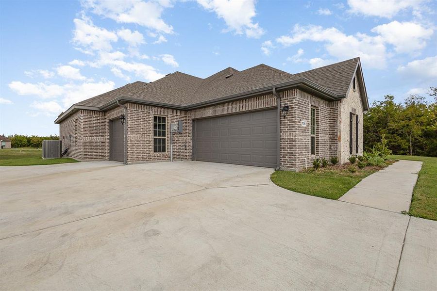 View of front of property featuring a garage, central air condition unit, and a front yard