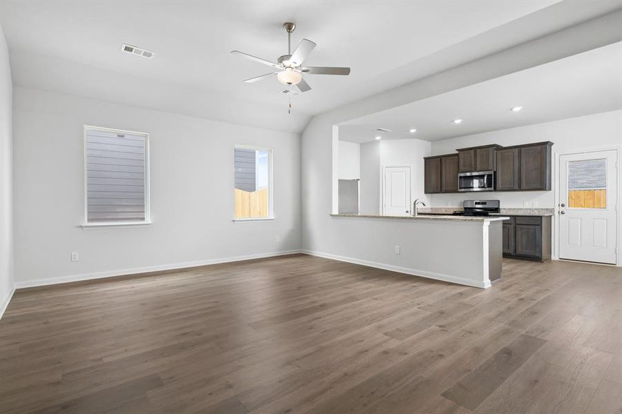 Unfurnished living room with dark wood-type flooring, ceiling fan, and recessed lighting Unfurnished living room with dark wood-type flooring, ceiling fan, and recessed lighting
