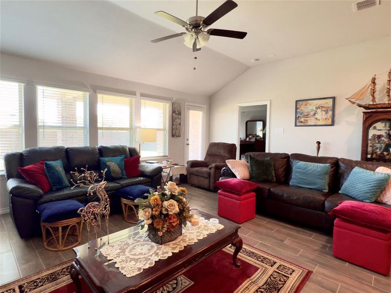 Living room with vaulted ceiling, wood finish floors, and ceiling fan Living room with vaulted ceiling, wood finish floors, and ceiling fan