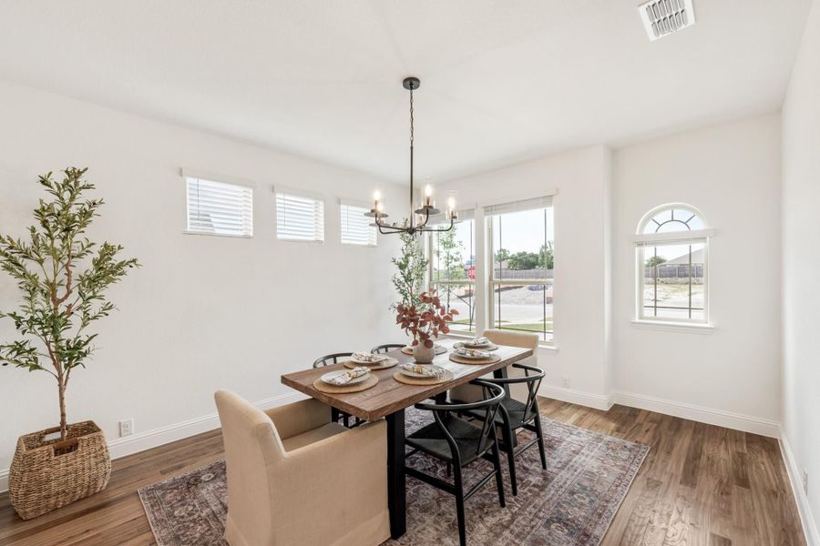 Dining room with wood table, black chandelier, hardwood floors, and arched window