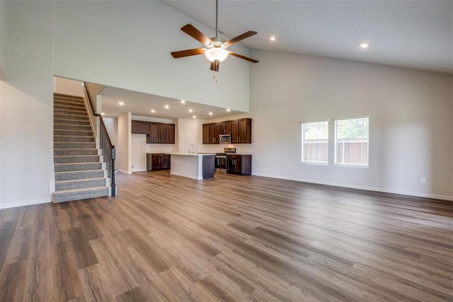 Unfurnished living room with high vaulted ceiling, sink, ceiling fan, and light hardwood / wood-style floors