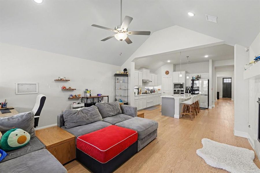 Open-concept living space featuring wood-finish flooring, a vaulted ceiling, and recessed lighting