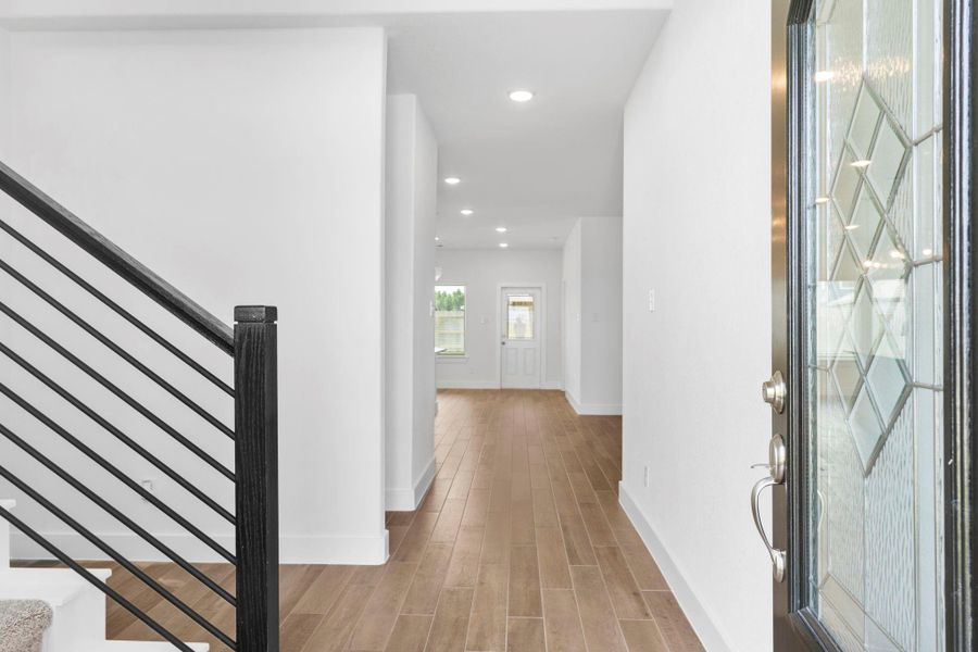 Dramatic two-story foyer with gorgeous carefree wood-look large plank tile flooring leading into the open living areas.