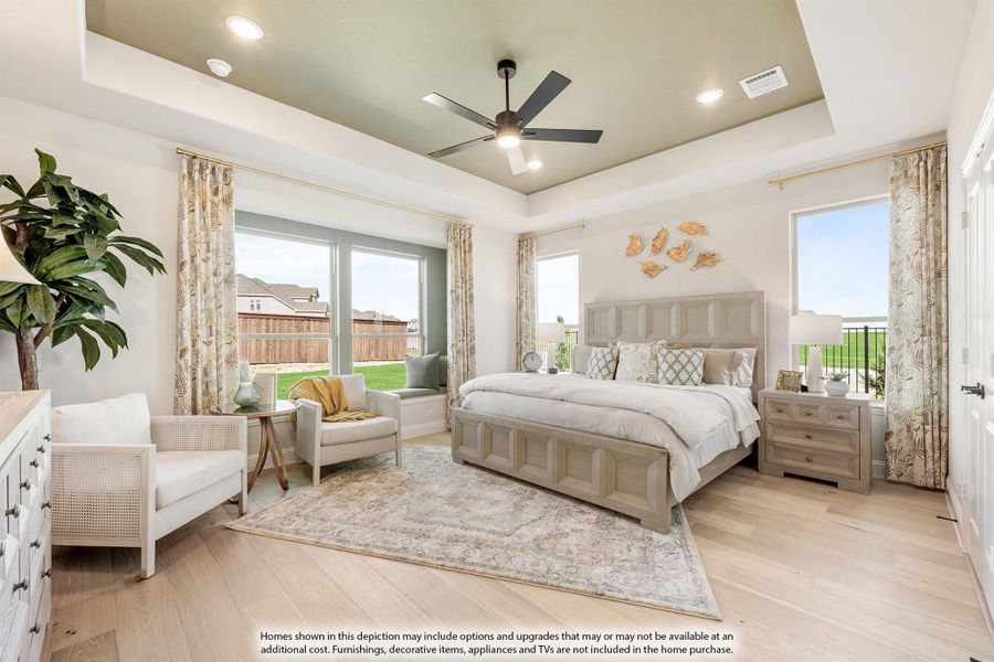 Master bedroom with tray ceiling, ceiling fan, hardwood floors, and large windows with backyard views