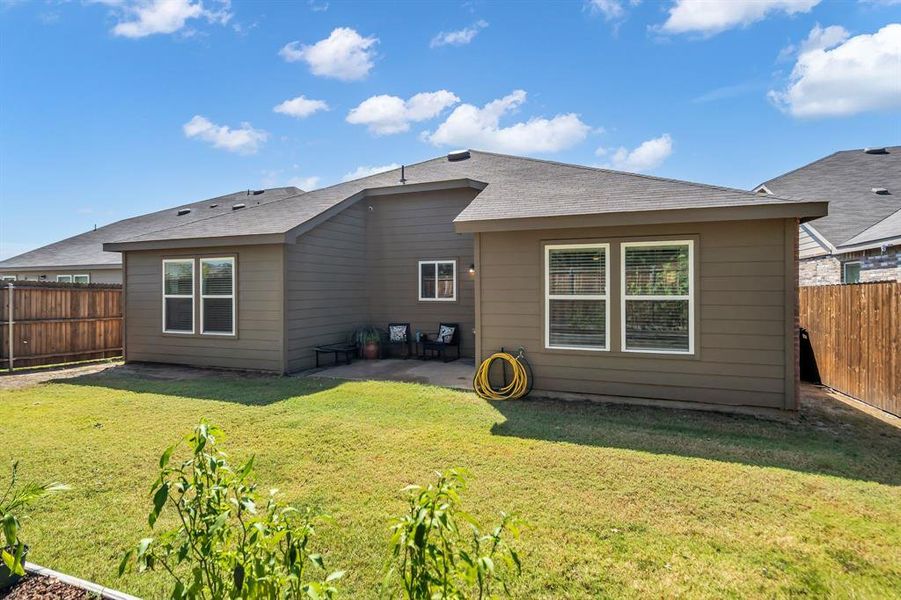 Rear view of property with a fenced backyard, a patio area, and roof with shingles