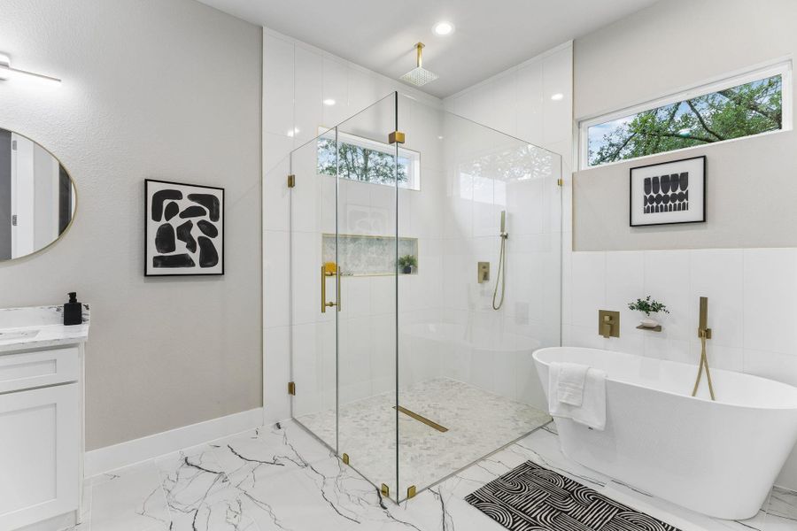 A refined bathroom featuring a spacious walk-in shower and a free-standing tub, accented with elegant gold fixtures.