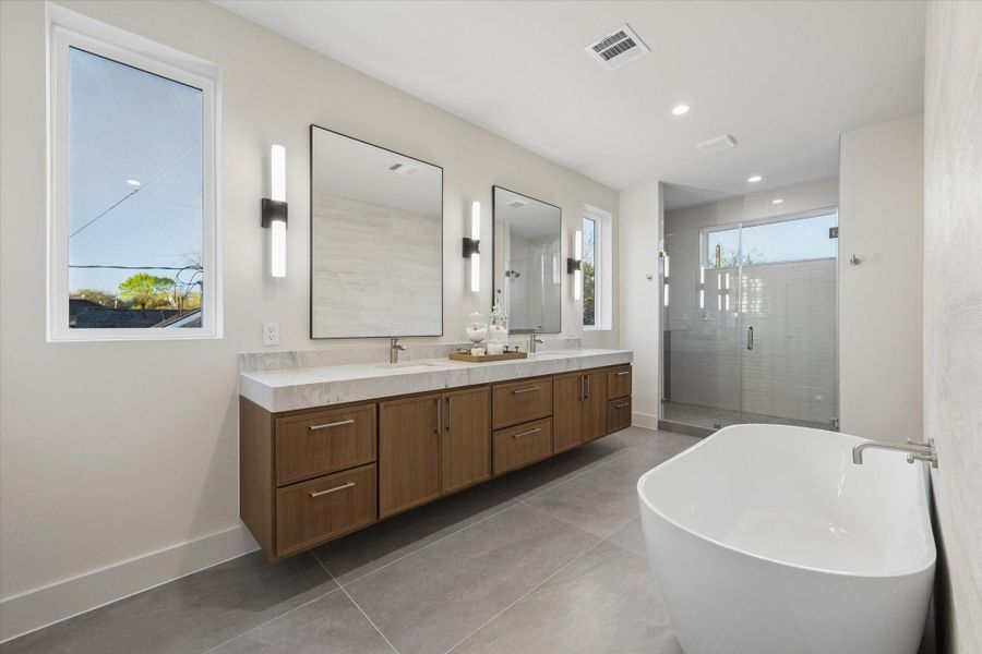 Your personal spa retreat awaits, featuring a 10-foot floating vanity with polished dolomite countertop, a soaking tub, and a luxurious frameless shower with dual showerheads.
