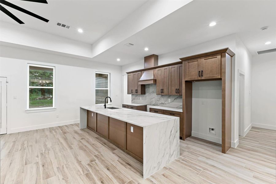 This modern kitchen features sleek wooden cabinets, a large quartz waterfall island with a built-in sink, and spacious, light-filled interiors. The open layout and contemporary design make it ideal for both cooking and entertaining. This modern kitchen features sleek wooden cabinets, a large quartz waterfall island with a built-in sink, and spacious, light-filled interiors. The open layout and contemporary design make it ideal for both cooking and entertaining.