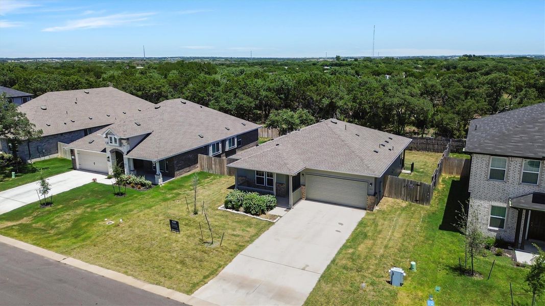 An aerial perspective reveals two modern homes nestled amidst green lawns and a verdant tree line.