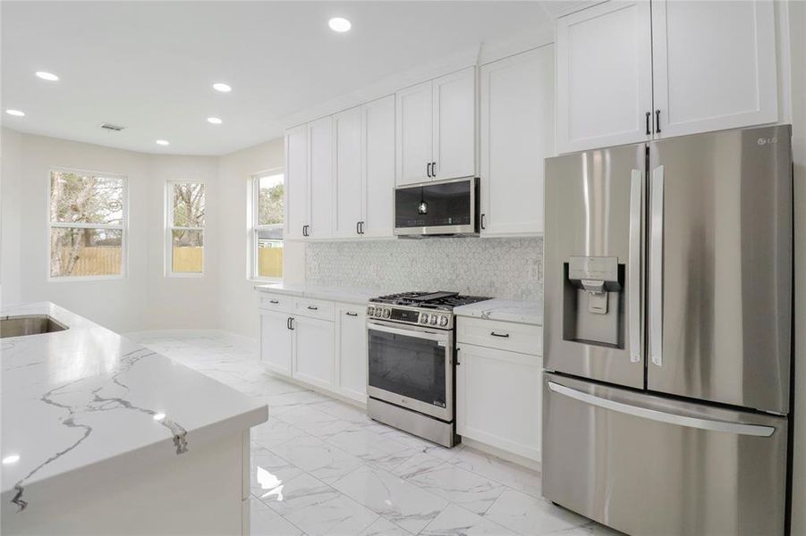 Kitchen with quartz countertops and soft close cabinets. The microwave, oven range, and refrigerator included.