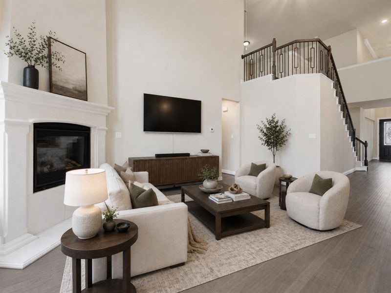 Two-story living area featuring a fireplace with a detailed mantel, wood-finish flooring, and a staircase with wrought iron balusters