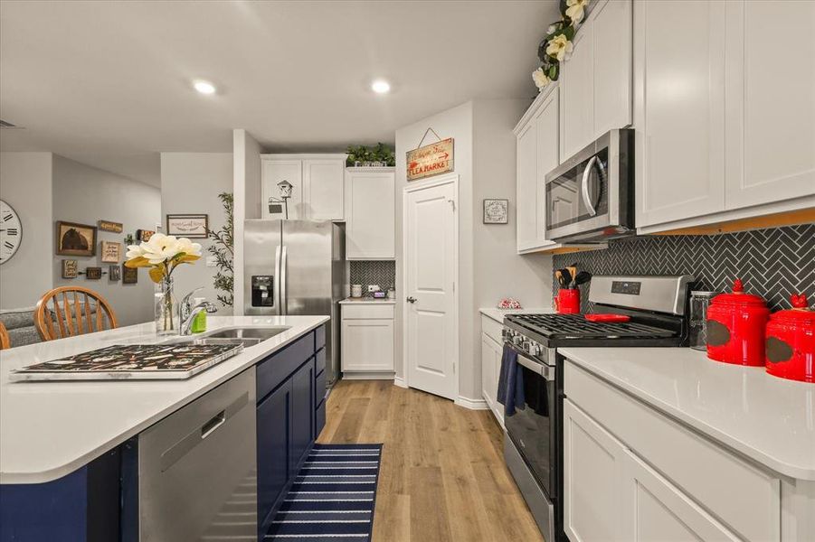 Kitchen with appliances with stainless steel finishes, white cabinets, light countertops, light wood-type flooring, and recessed lighting Kitchen with appliances with stainless steel finishes, white cabinets, light countertops, light wood-type flooring, and recessed lighting