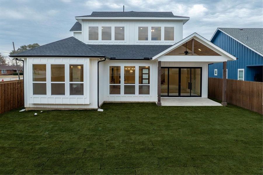 Back of house featuring a fenced backyard, a shingled roof, a patio, and board and batten siding