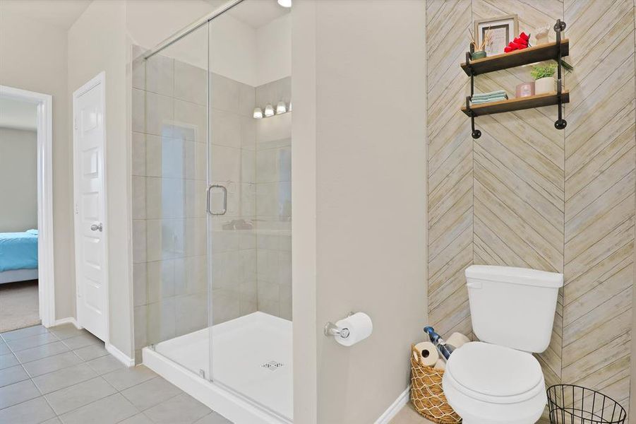 Bathroom featuring tile patterned floors, toilet, and a shower with shower door