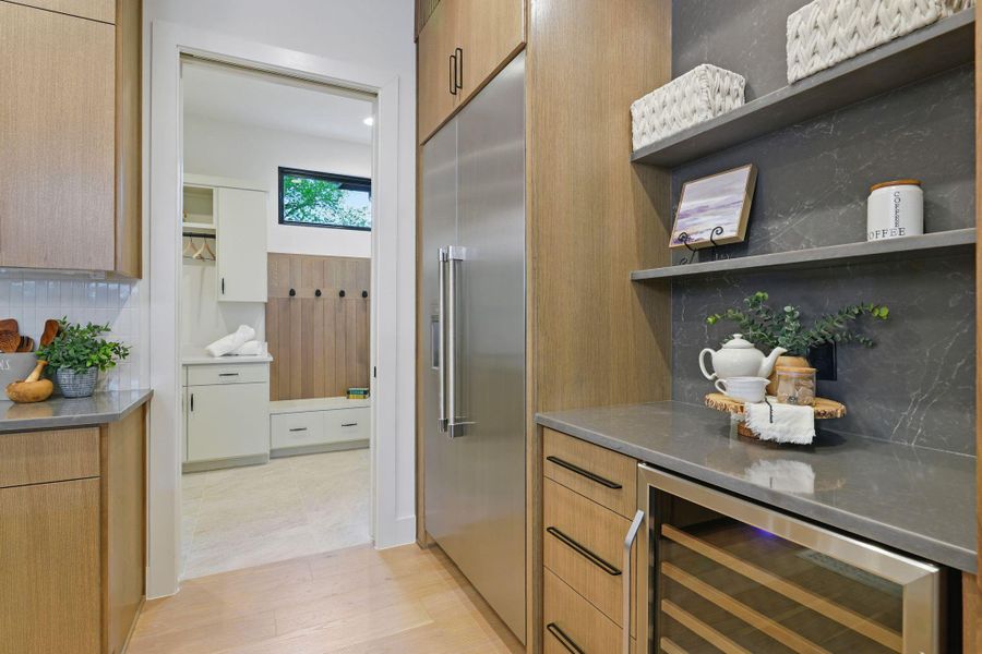 Kitchen with built in fridge, open shelves, wine cooler, decorative backsplash, and light wood-type flooring