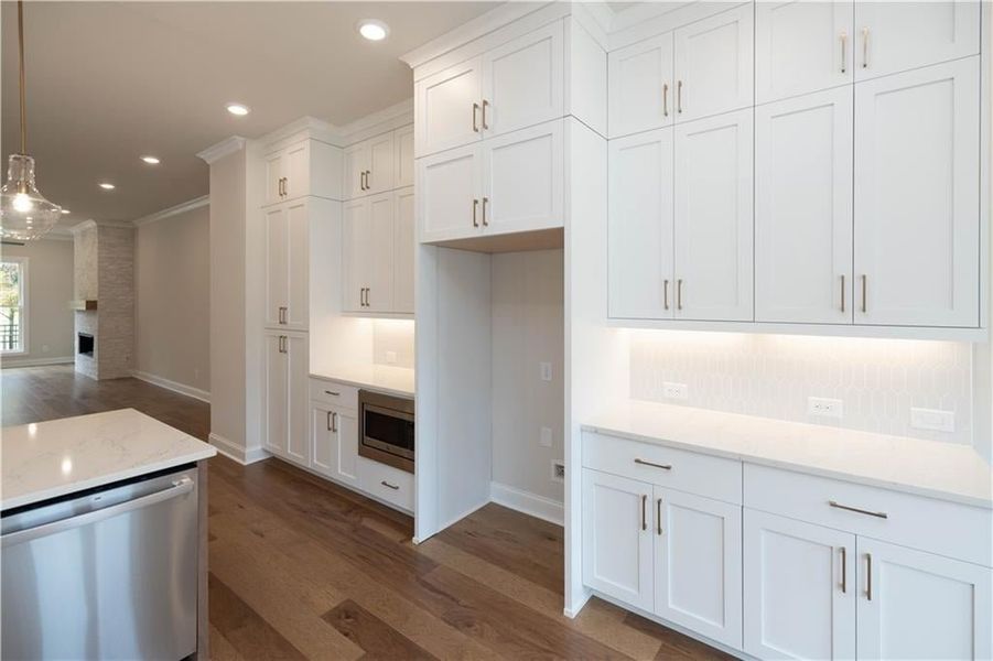 Kitchen with white cabinetry, decorative light fixtures, dark hardwood / wood-style flooring, stainless steel appliances, and light stone countertops