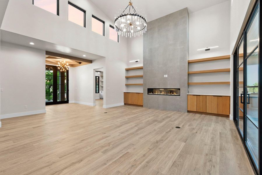 A grand living area showcases soaring ceilings, a modern linear fireplace, and warm wood flooring.