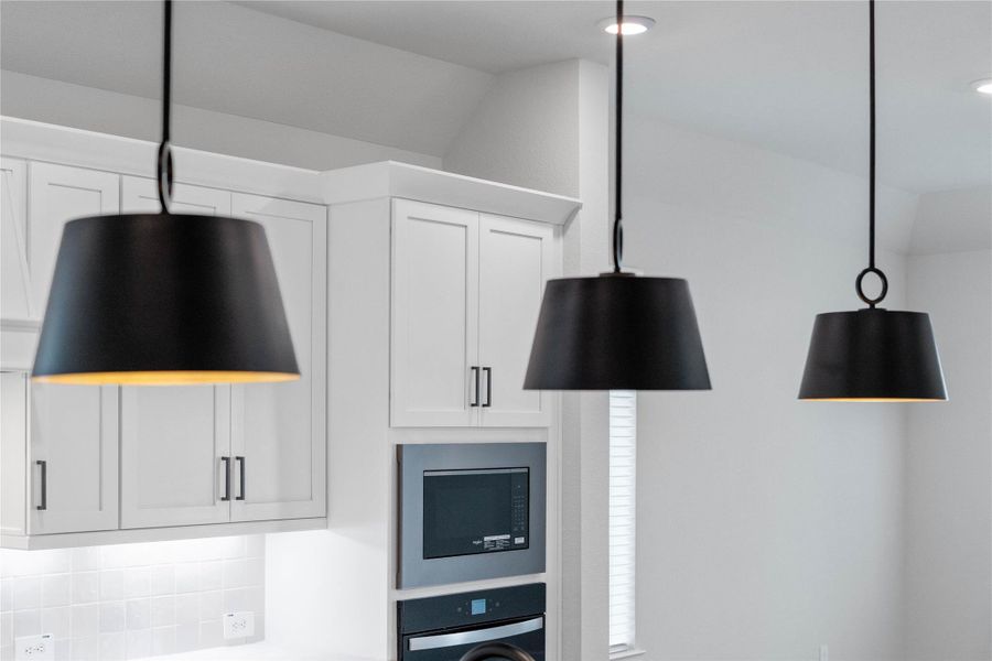 Trio of modern matte black pendant lights that elegantly hang above the kitchen island, providing focused task lighting and a touch of refined style.