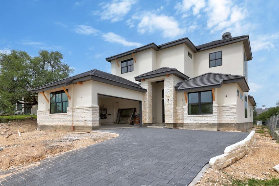 Contemporary stucco and stone-clad exterior with a paved driveway