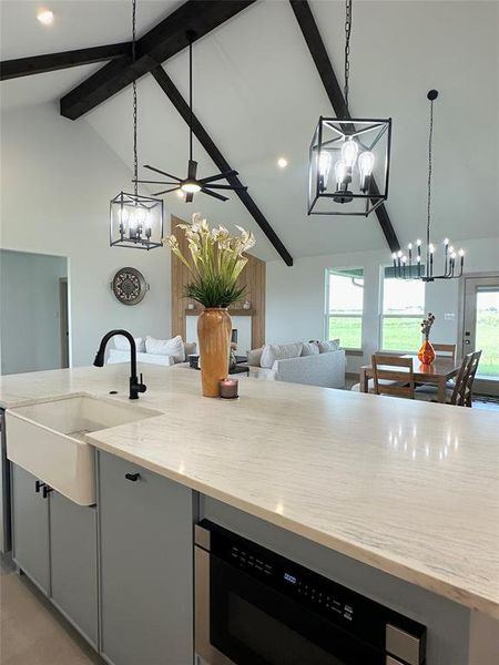 Kitchen with pendant lighting, a chandelier, gray cabinets, beamed ceiling, and high vaulted ceiling