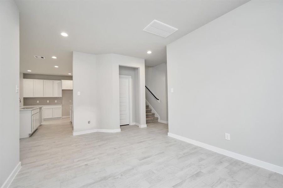 This expansive dining room showcases sophisticated flooring, custom paint, and seamlessly connects to the family room and kitchen, providing an open and inviting atmosphere. Sample photo of completed home with similar floor plan. As-built interior colors and selections may vary.