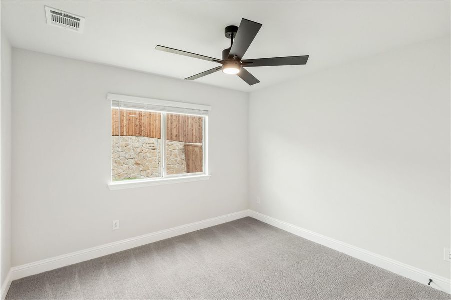 Empty bedroom with gray carpet, white walls, ceiling fan, and single window Empty bedroom with gray carpet, white walls, ceiling fan, and single window
