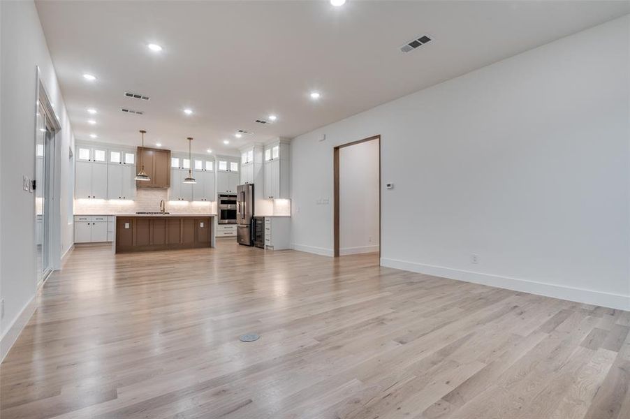Unfurnished living room with light wood-type flooring and recessed lighting Unfurnished living room with light wood-type flooring and recessed lighting