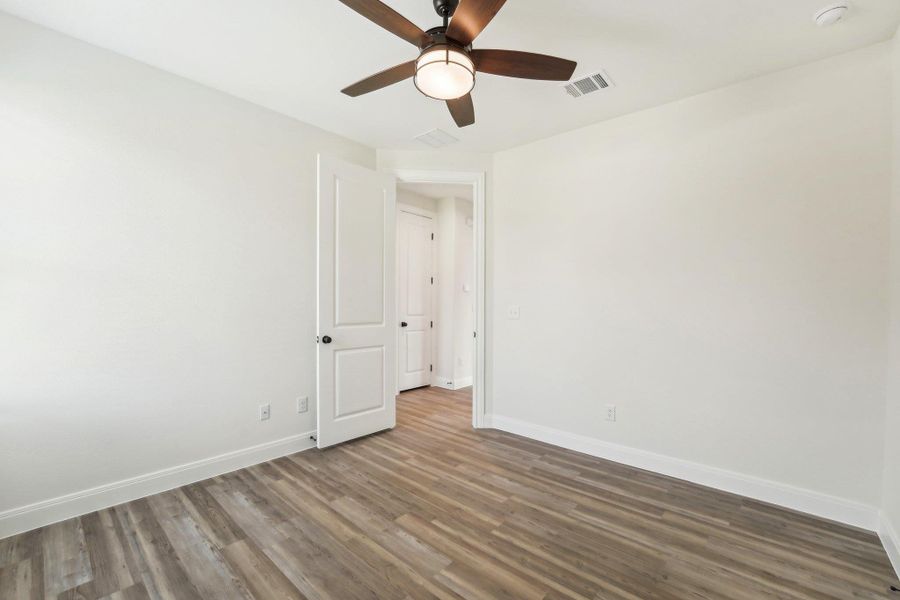 Bedroom 2 with baseboards, a ceiling fan, wood-style vinyl flooring, and visible vents Bedroom 2 with baseboards, a ceiling fan, wood-style vinyl flooring, and visible vents