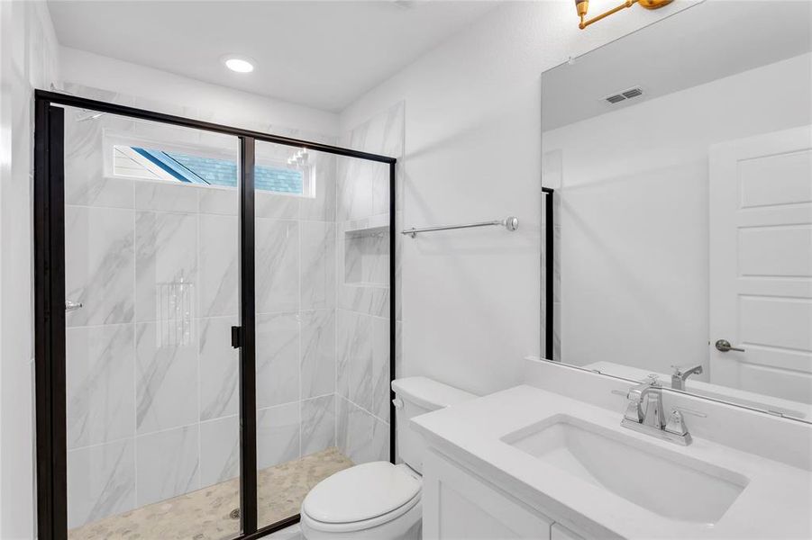 Full bath featuring a marble finish shower and vanity