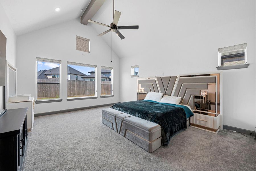 Spacious primary suite with soaring ceilings, plush carpeting, and large windows for natural light.