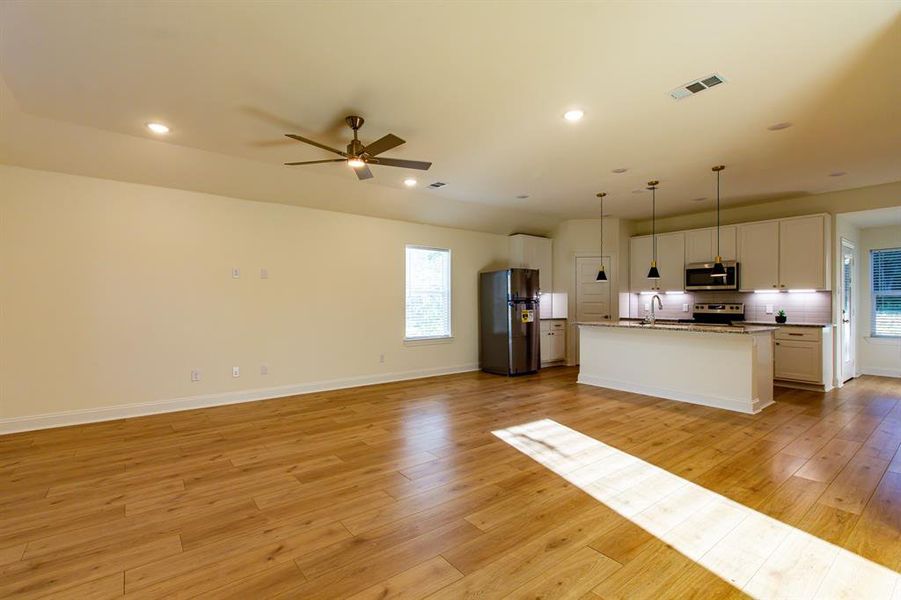 Kitchen featuring open floor plan, appliances with stainless steel finishes, light wood-style floors, a center island with sink, and recessed lighting Kitchen featuring open floor plan, appliances with stainless steel finishes, light wood-style floors, a center island with sink, and recessed lighting