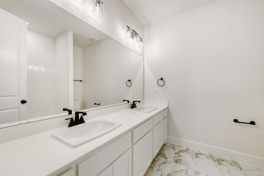 Bathroom featuring double vanity and light marble finish flooring
