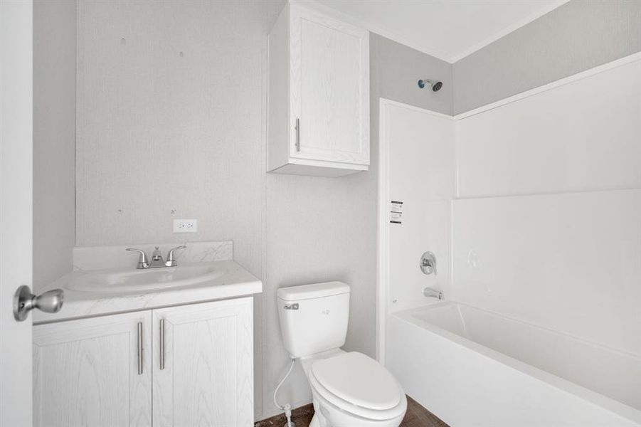 Bathroom featuring a white vanity with integrated sink, chrome faucet, white toilet, and a white tub with shower