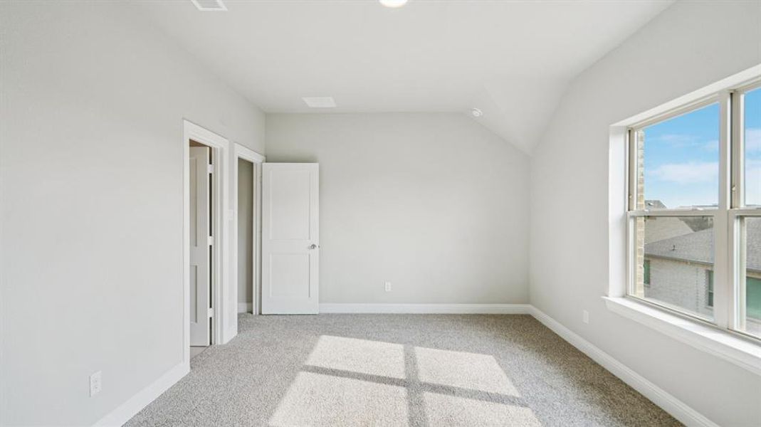 Unfurnished bedroom with light carpet and vaulted ceiling Unfurnished bedroom with light carpet and vaulted ceiling