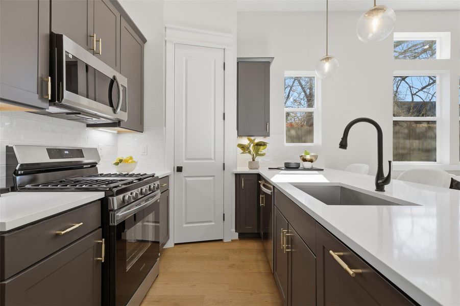 This sleek kitchen boasts modern cabinets, gleaming countertops, and stainless steel appliances, all illuminated by natural light and elegant pendant fixtures. This sleek kitchen boasts modern cabinets, gleaming countertops, and stainless steel appliances, all illuminated by natural light and elegant pendant fixtures.