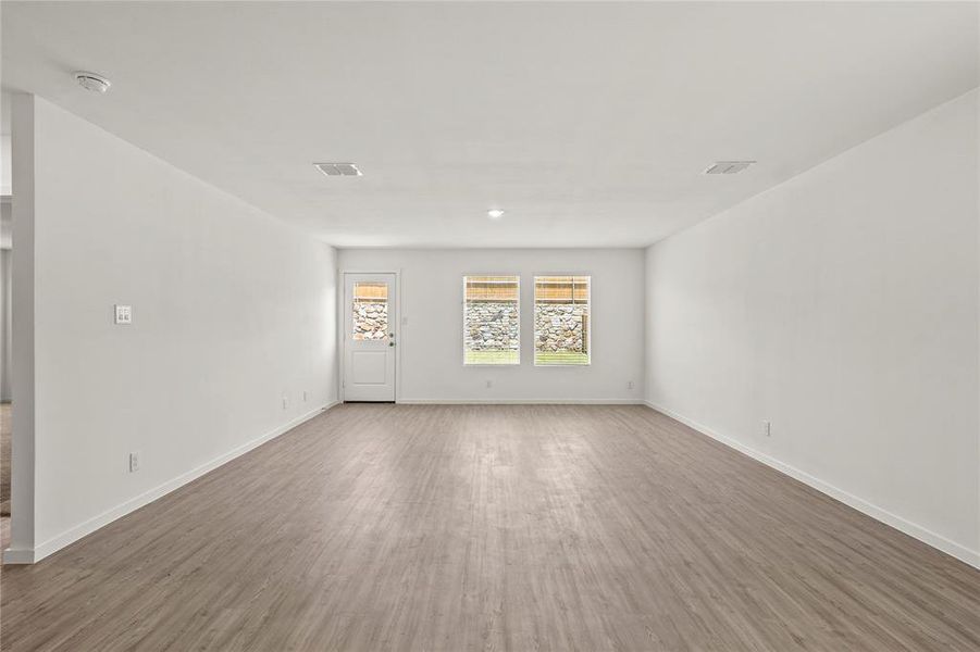 Spacious interior room featuring wood-finish flooring, white walls, and recessed lighting