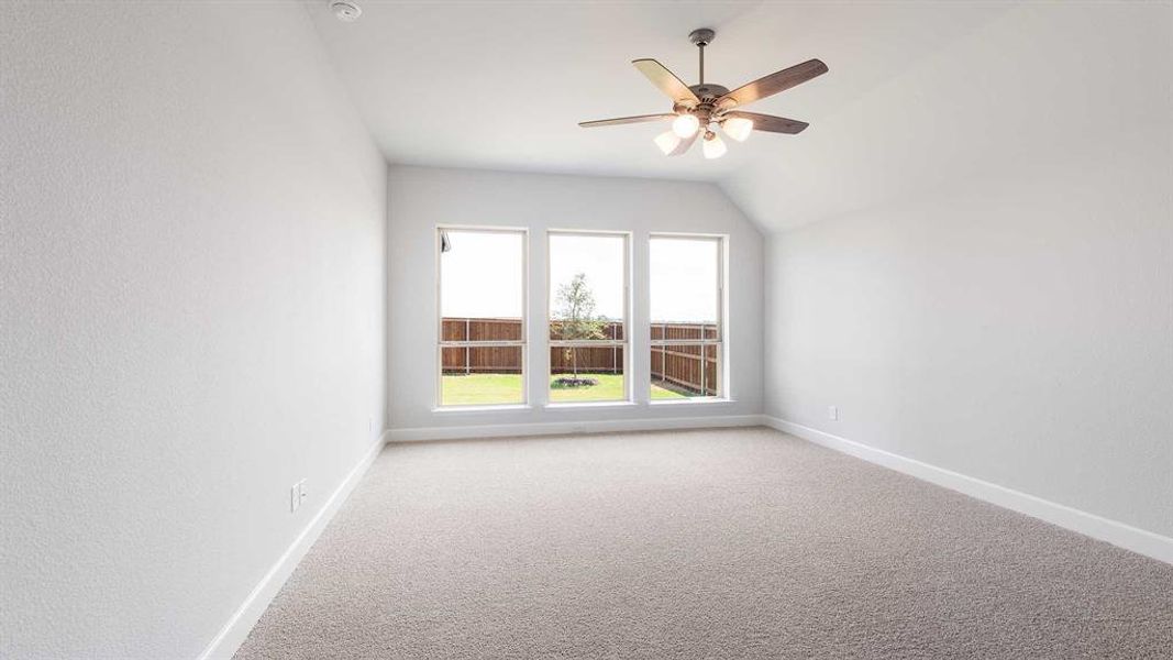 Unfurnished room featuring light carpet, lofted ceiling, and ceiling fan