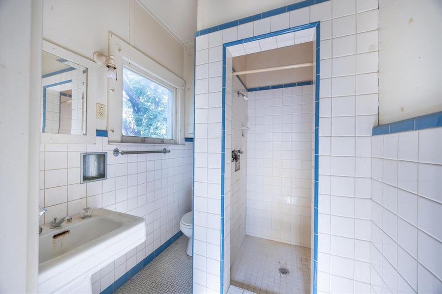 Bathroom featuring tile walls, a tile shower, toilet, and tile patterned flooring