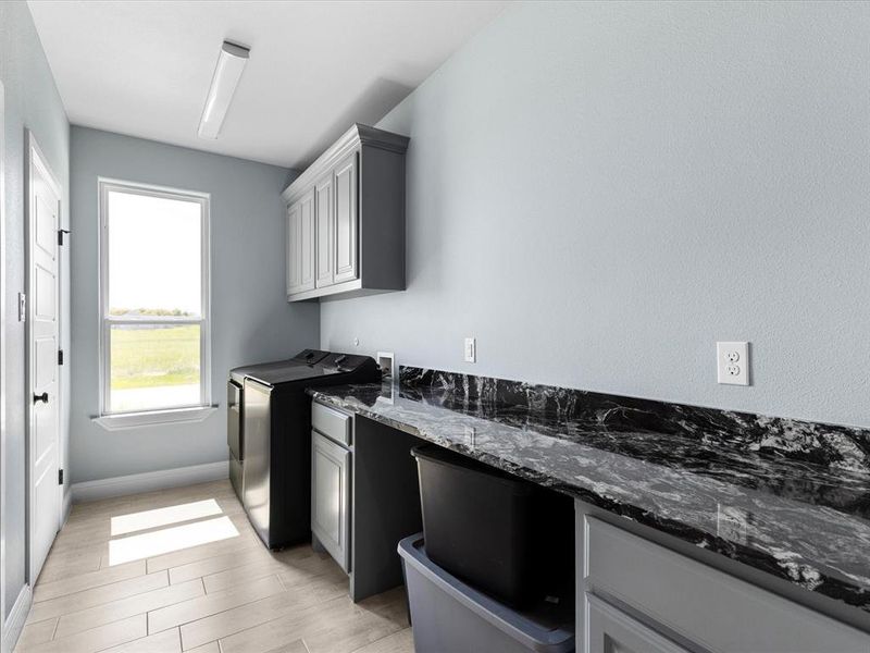 Laundry area featuring cabinet space, wood tiled floors, and separate washer and dryer Laundry area featuring cabinet space, wood tiled floors, and separate washer and dryer