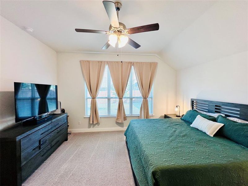 Carpeted bedroom featuring vaulted ceiling and ceiling fan