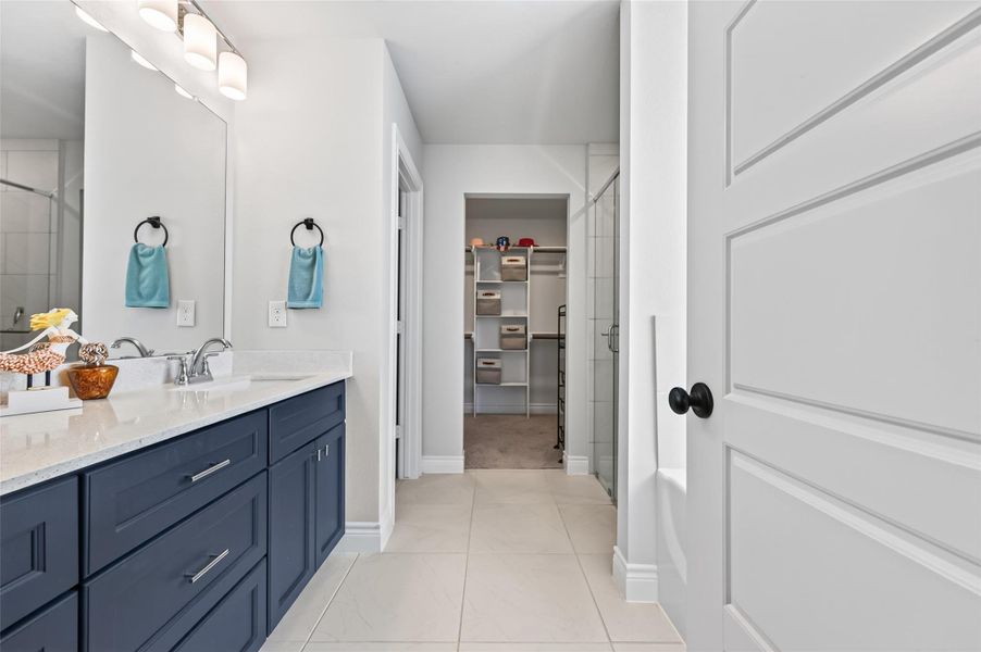This elegant primary bathroom features a modern design aesthetic, highlighted by premium quartz countertops and a functional double vanity with high-end fixtures. The space is thoughtfully laid out to maximize comfort and convenience, leading directly into a spacious, well-organized walk-in closet that provides ample storage capacity for a contemporary lifestyle. This elegant primary bathroom features a modern design aesthetic, highlighted by premium quartz countertops and a functional double vanity with high-end fixtures. The space is thoughtfully laid out to maximize comfort and convenience, leading directly into a spacious, well-organized walk-in closet that provides ample storage capacity for a contemporary lifestyle.